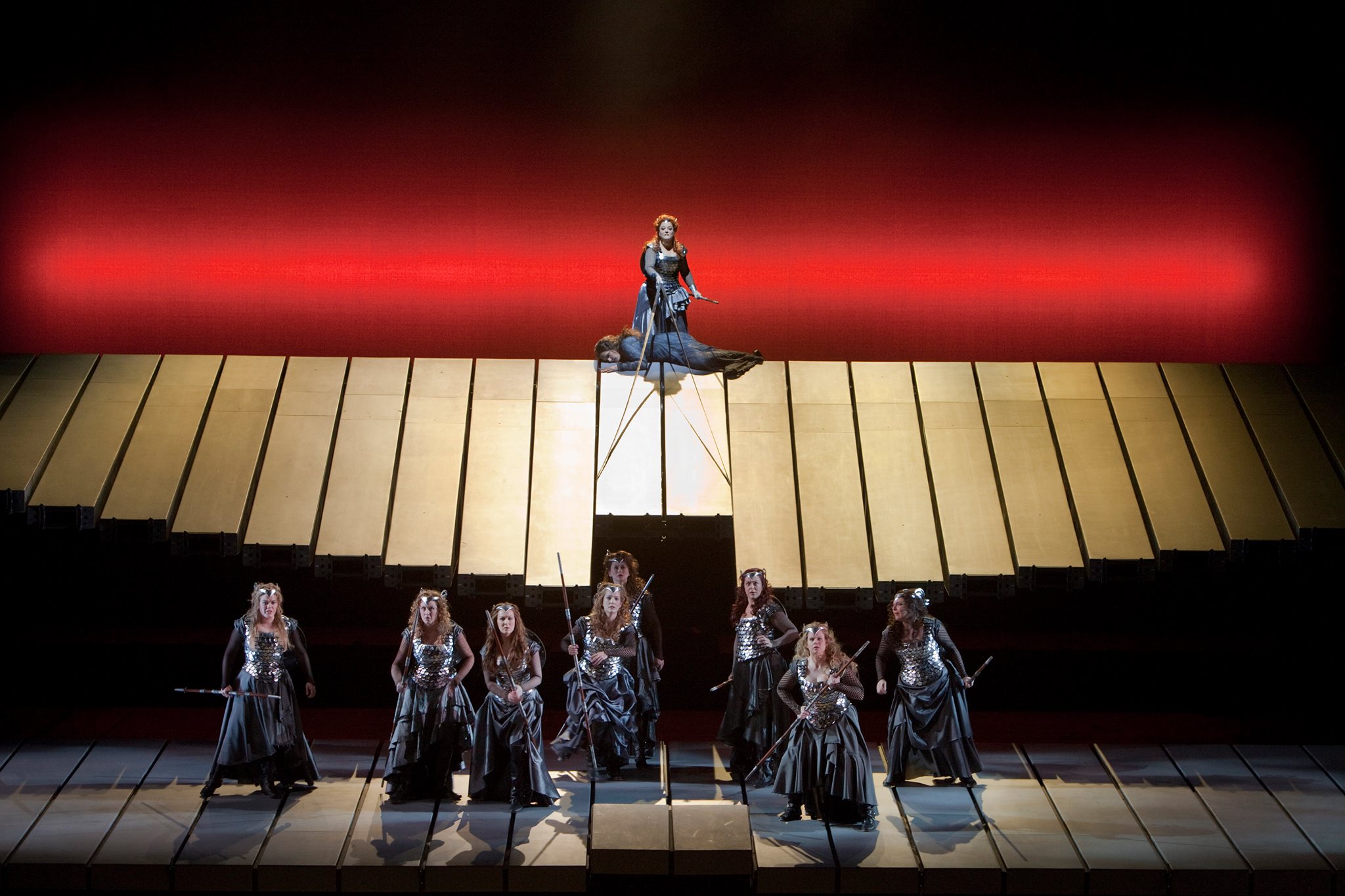 Spear-wielding women dressed as Valkyries set against a red backdrop